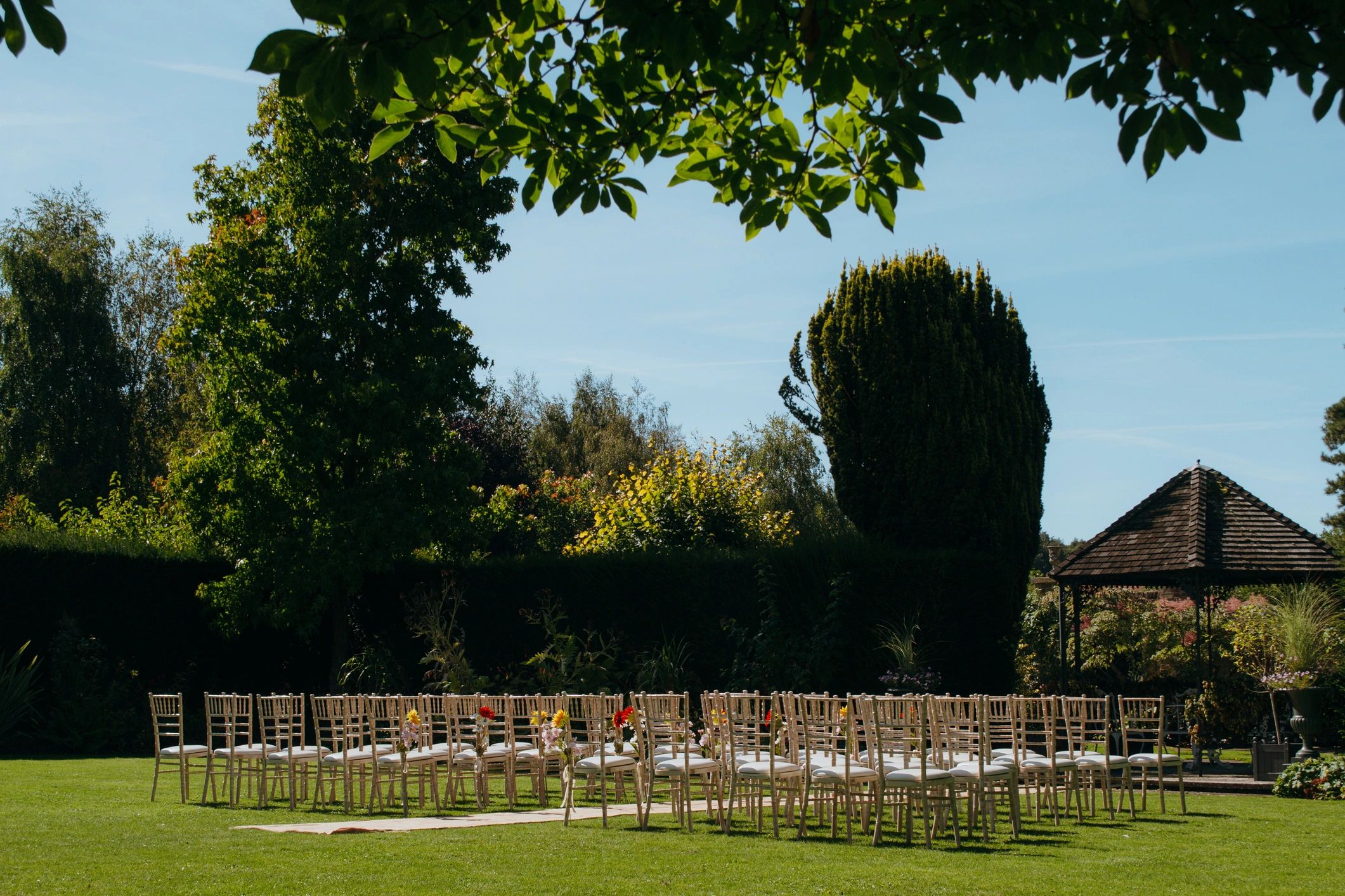 Wedding Ceremony on Lawn Outside in Summer with White Chairs and Orange Flowers